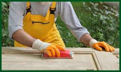 A man sanding a wooden board with a sanding block